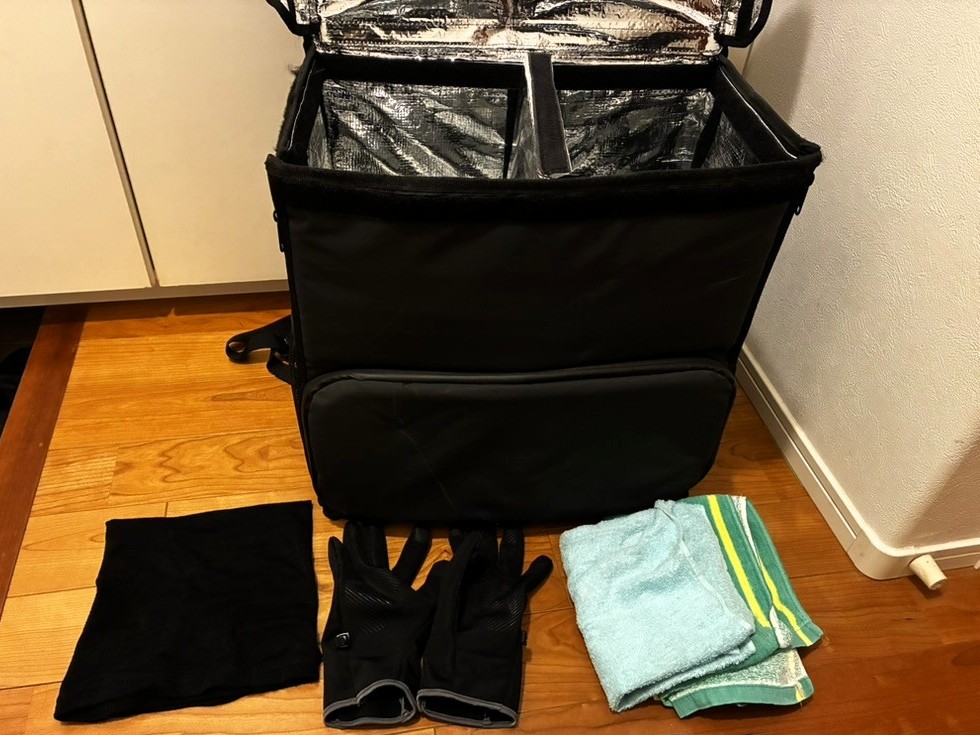 ムタさんが配達に持参する持ち物一式。スマホ・タオル・手袋・ネックウォーマーのシンプル構成。