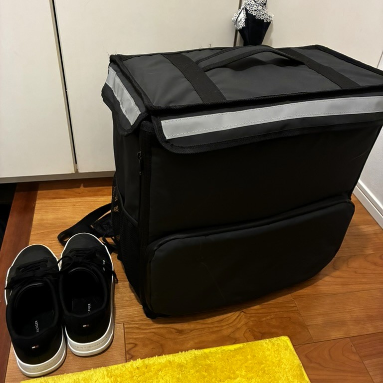 ムタさんが使用するロゴなし配達バッグ。シンプルなブラックデザインで他社デリバリーにも転用できる