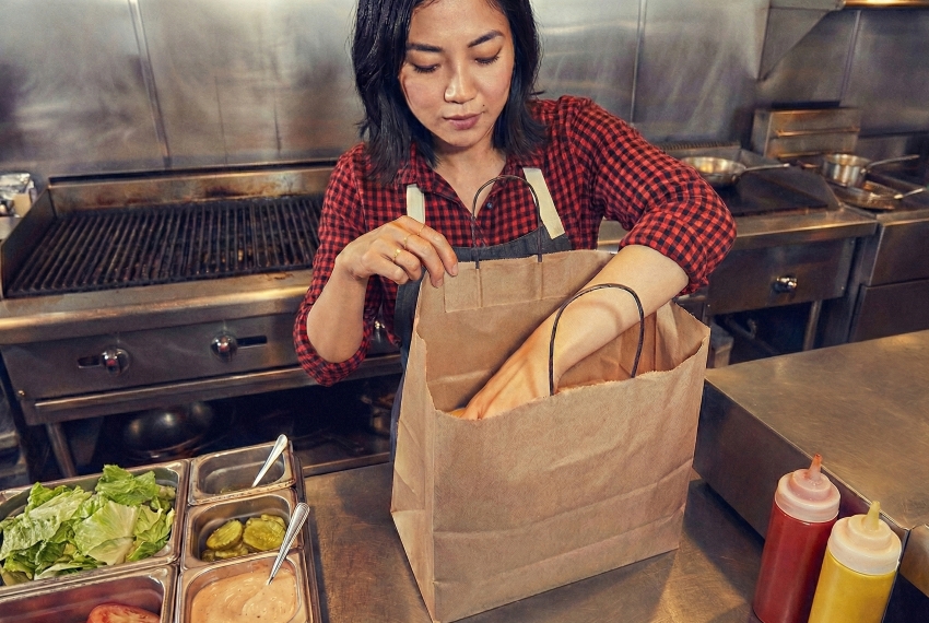 飲食店の厨房でのフードデリバリー用の商品を梱包している風景。実店舗運営の知見を示すイメージ。
